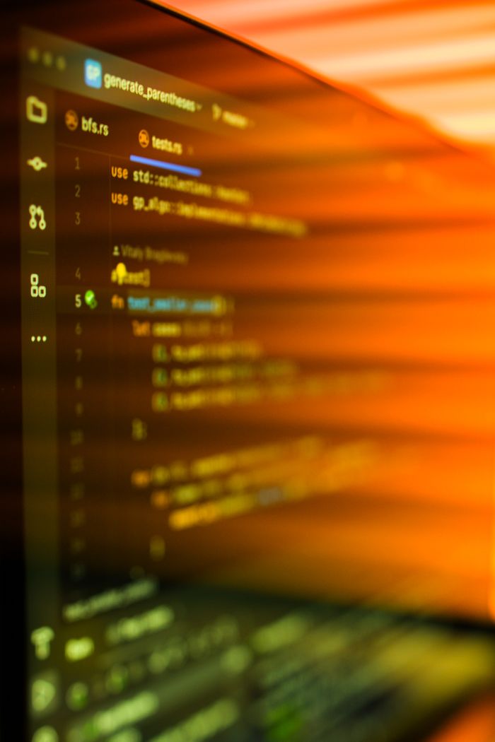 services-02 Vibrant, motion-blurred view of programming code on a computer screen with an abstract orange glow.