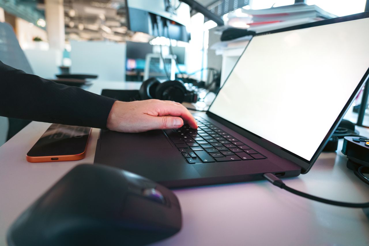 services-01 Hand typing on a laptop keyboard in a sleek office environment, showcasing modern technology.